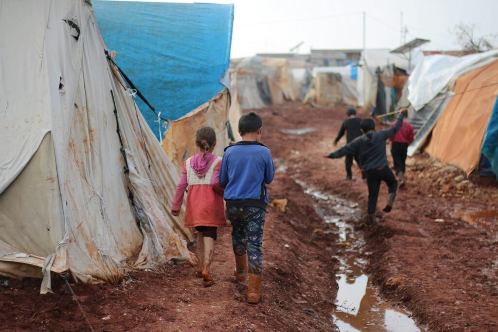 Children walk through a muddy refugee camp in Idlib, Syria.