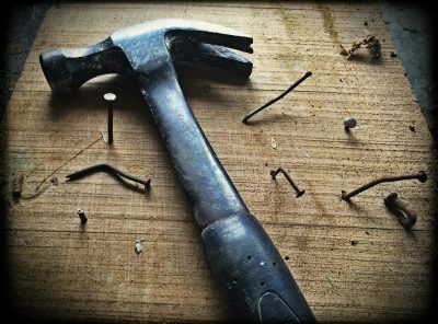 A weathered hammer surrounded by bent nails on a wooden plank, capturing the essence of carpentry work.